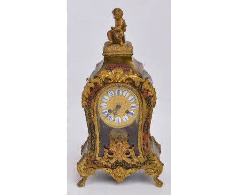 An early 20th century French simulated boullework mantel clock surmounted with a figure of a child, the circular dial set wit