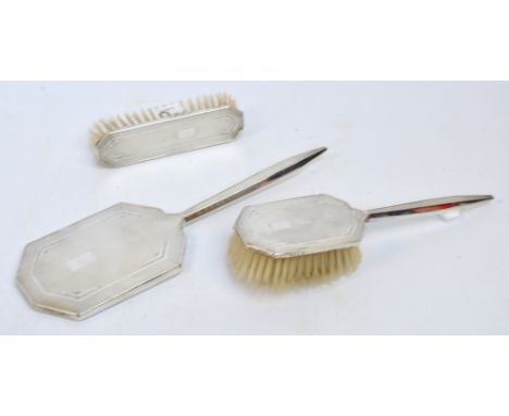 An Elizabeth II Art Deco design hallmarked silver three piece dressing set comprising mirror, clothes brush and hair brush, B