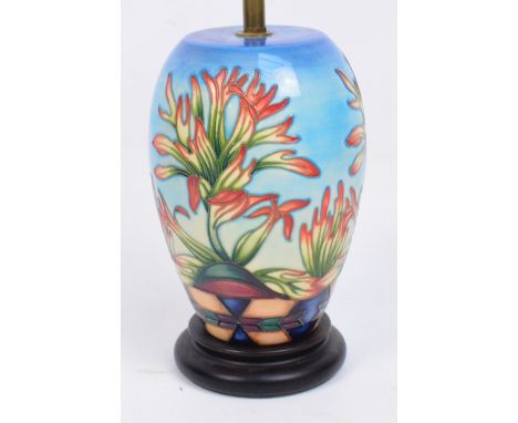 A modern Moorcroft lamp base in "Indian Paintbrush" pattern by Philip Gibson, on a graduated blue ground, raised on small cir