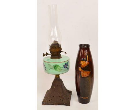 A late 19th century oil lamp on cast iron base, height to top of chimney, 56cm, also a brown glazed vase decorated in relief 