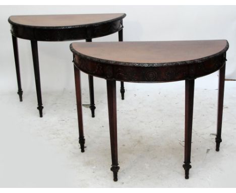 A pair of Edwardian mahogany Adam revival demi-lune side tables with carved moulded tops above foliate decorated frieze and f