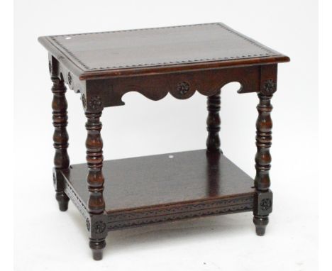 A carved oak two tier rectangular side table raised on ring turned and block supports, width 76cm.