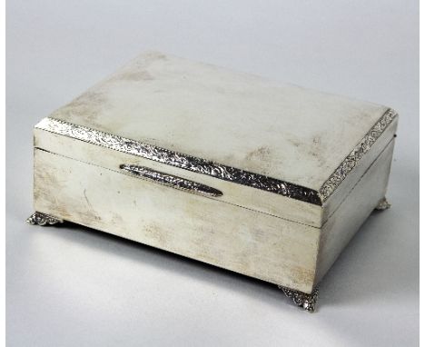 A silver cigarette box, Birmingham 1975, with engraved foliate border, raised on four feet, 16.5cm wide Condition Report: Ove