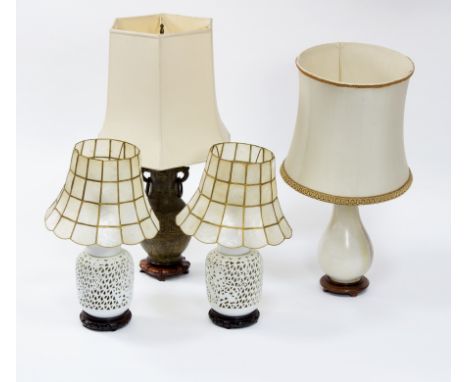 A pair of Chinese porcelain lamps on hardwood stands with shell shades, a bronzed twin-handled baluster lamp and an onyx balu