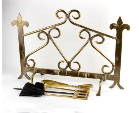 A brass fireguard with scrolling decoration, 102cm wide and a set of fire irons