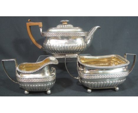 GEORGE III THREE PIECE SILVER TEA SERVICE of oval fluted form with wicker banding and egg and dart borders, with dragon crest