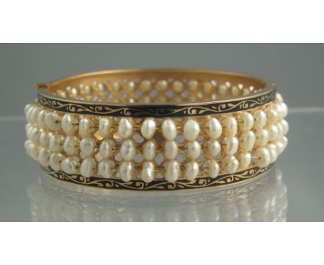 HINGED TRIPLE ROW PEARL BANGLE. The unmarked yellow gold bangle set with three rows of freshwater cultured pearls with a blac