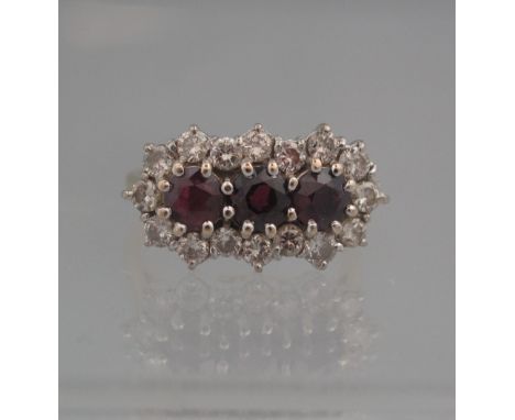 18CT GOLD RUBY AND DIAMOND TRIPLE CLUSTER RING. Each deep red ruby estimated 4mm diameter surrounded by diamonds. Ring size M