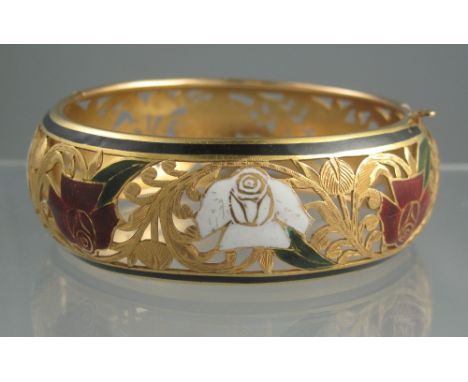 UNMARKED YELLOW GOLD BANGLE. Pierced and engraved with flowers and foliage with roses picked out in red and white enamel. Pul