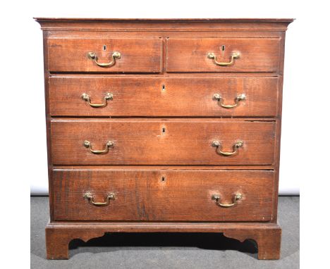 A George III oak chest of drawers, rectangular boarded top above a cavetto frieze, two short and three long graduating drawer
