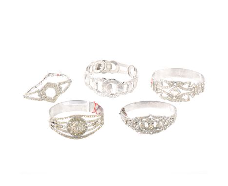 Four paste set costume jewellery bangles, one having expanding links to the back, a rhodium-plated bangle with floral and scr