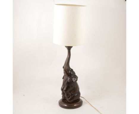 A carved hardwood table lamp, in the form of a elephant, sitting and balancing a ball on the end of its trunk, 43cm.