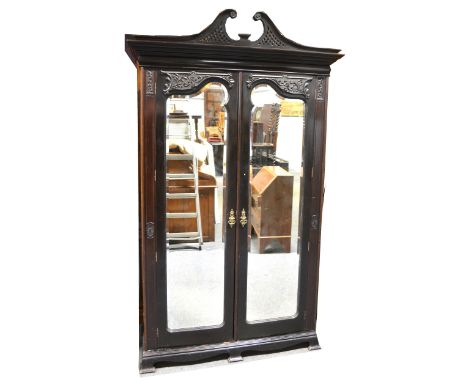 A late Victorian carved mahogany double wardrobe, swan-neck and pierced pediment, moulded cornice, two mirror panelled doors,