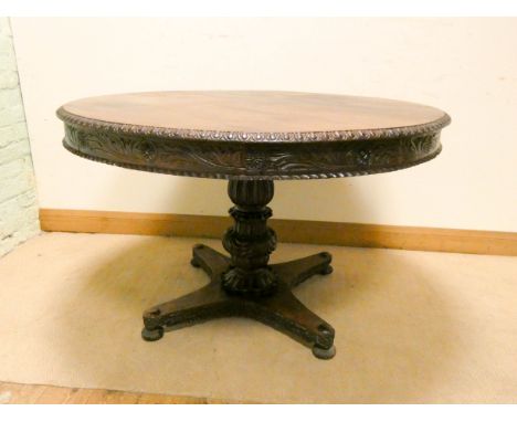 A circular Regency rose wood centre table with carved and pie crust edge standing on carved single pillar base with four bran
