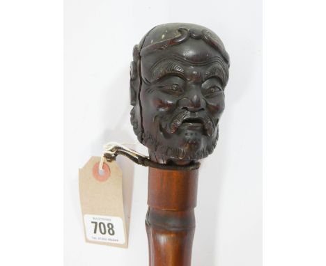 A short bamboo walking stick weighted at one end with a large brass ferrule, the handle carved as an old man with a beard and