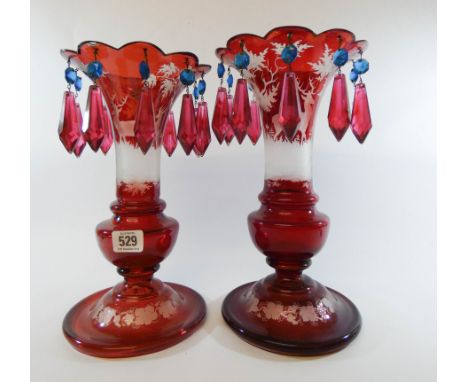 A pair of Bohemian ruby red glass lustres decorated with deer's and stags in a forest setting, overall height 30cms   A littl