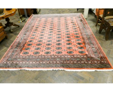 Pink patterned Bokhara design wool pile carpet, approximately 10'6 x 8'3