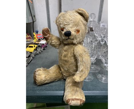 A VINTAGE JOINTED TEDDY BEAR WITH A THE REMAINS OF A LABEL ON IT HEIGHT APPROX 35CM 