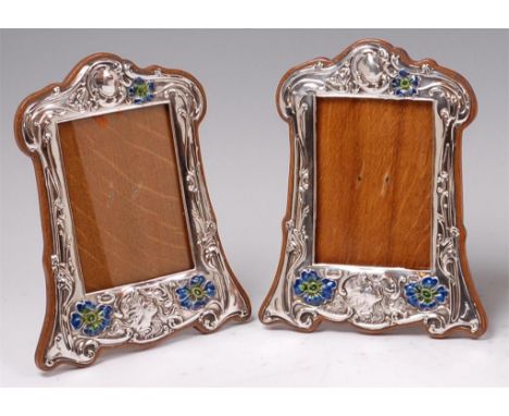 A pair of Art Nouveau silver and enamel photograph frames, the silver of embossed stylised floral and figural form, with oak 