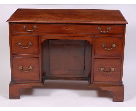 An antique mahogany kneehole desk, having an arrangement of five drawers over a centre kneehole, with recessed cupboard door,