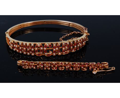 A 15ct gold, ruby and seed pearl set hinged bangle, Bannockburn, with safety chain, 13.6g, dia. 6cm, in green leather fitted 