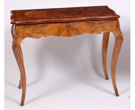 A Victorian figured walnut and marquetry inlaid games table, the fold-over serpentine top marquetry inlaid with trailing flow