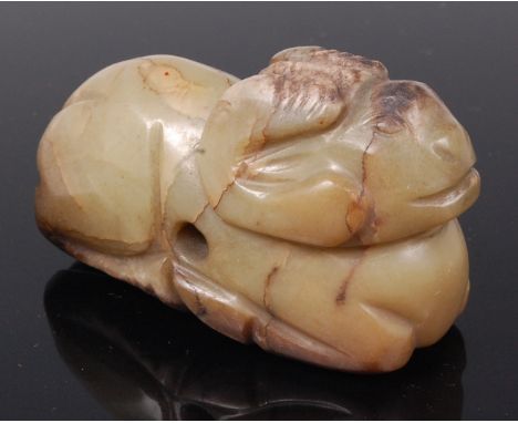 A Chinese celadon and russet jade pendant carving of a ram, in recumbent pose, 7.2cm