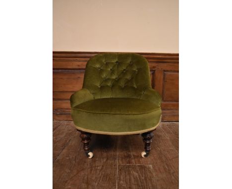 A Victorian tub shaped nursing chair in buttoned upholstery on turned tapering supports resting on ceramic casters. H.74 W,62