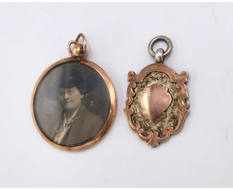 A 9ct gold pendant frame of double sided circular form and a silver fob or medal with applied gold shield and border, present