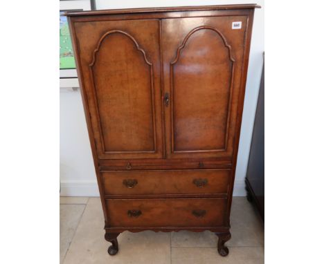 An early 20th century walnut veneered drinks cabinet, the two panel doors opening to reveal shelves, above brushing slide, ov