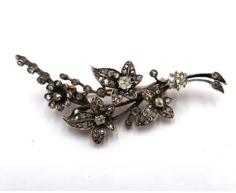 An early 20th century diamond foliate brooch, set with old and rose cut diamonds. The larger old cut diamond to the base of t
