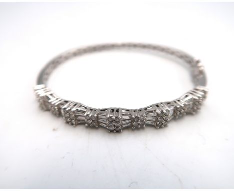 A 14ct gold baguette and brilliant cut diamond hinged bangle. Estimated total diamond weight 1.75cts. Estimated H/I SI. Weigh