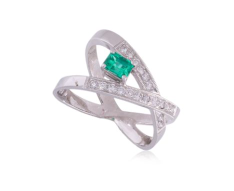 AN EMERALD AND DIAMOND CROSSOVER RING
Featuring an emerald cut emerald weighing approximately 0.25 Cts, mounted in a white go