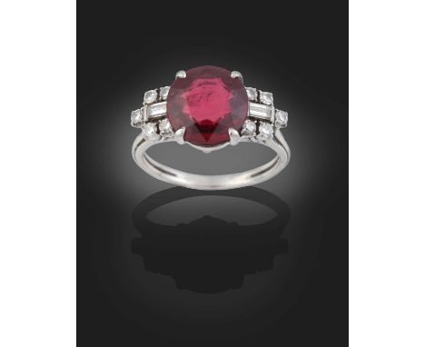 the round cut ruby flanked by baguette cut diamonds within borders of eight-cut diamonds, in white claw settings, to a parted