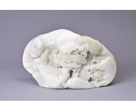 A CARVED PALE JADE BOULDER. Carved with two figures standing on pierced rockwork and trees, with pavilions in the background,