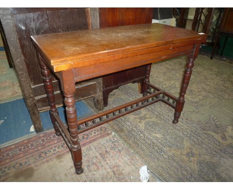 An Edwardian Mahogany flap-over Card Table having turned legs with spindle detail, 'H' stretcher and flap-over top having ins