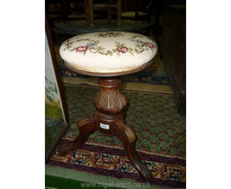A darkwood framed Piano Stool having turned and carved pillar, four splay carved detail feet, the floral tapestry upholstered