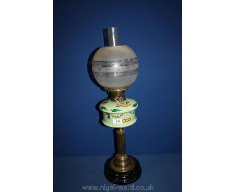 A brass column base oil lamp with green glass reservoir, chimney and etched globe shade.