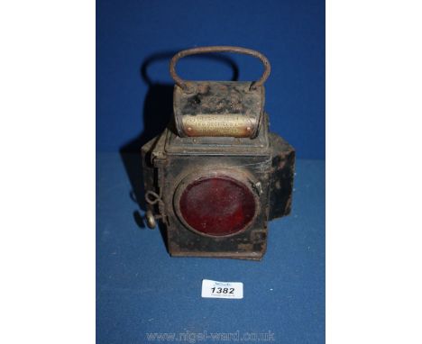 A Railway red illuminating tail-light having two angled, forward-facing bevelled glass windows, complete with paraffin burner