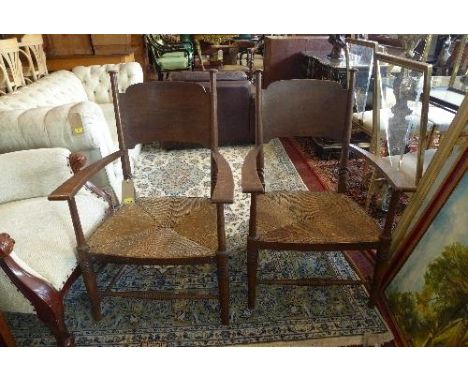 A pair of early 20th Century Arts and Crafts oak open armchairs, in the manner of Liberty, with rush seats and ring turned su