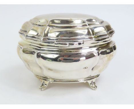 A silver tea caddy, by Goldsmiths and Silversmiths Co Ltd, London 1910, of oval shaped outline on four supports, hinged cover