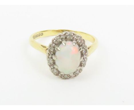 An 18ct gold opal and diamond cluster ring, the oval cabochon cut opal approximately 8mm x 5mm x 2.9mm deep, surrounded by a 