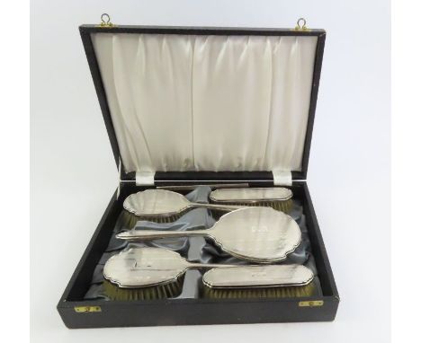 A cased silver dressing table set to include two hairbrushes, a hand mirror, two clothes brushes and a comb, Birmingham 1947 