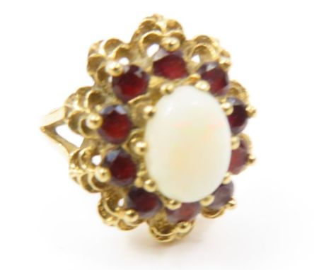 A 9ct gold opal and garnet dress ring, the oval opal surrounded by a row of garnets in a decorative high set mount, finger si