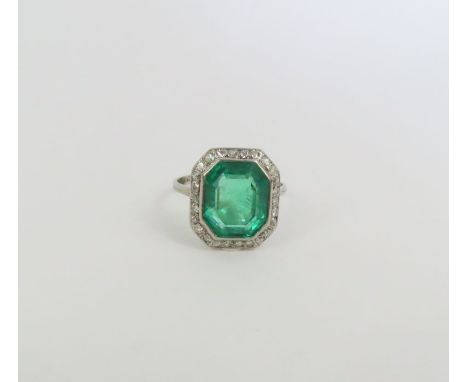 An impressive emerald and diamond dress ring, the emerald cut stone approximately 13.3mm x 11.3mm x 7.1mm, approximately 7.58