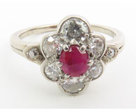 An unmarked white gold early 20th century ruby and diamond cluster ring, the single round ruby surrounded by six old cut diam