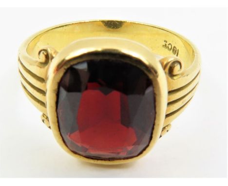 A garnet single stone ring, in rub-over setting with decorative shoulders, marked '18ct', finger size R 1/2, 6.7g gross