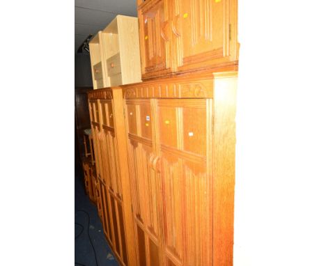 A LIGHT OAK LINENFOLD SEVEN PIECE BEDROOM SUITE, comprising a two double door wardrobe, dressing table with a triple mirror, 