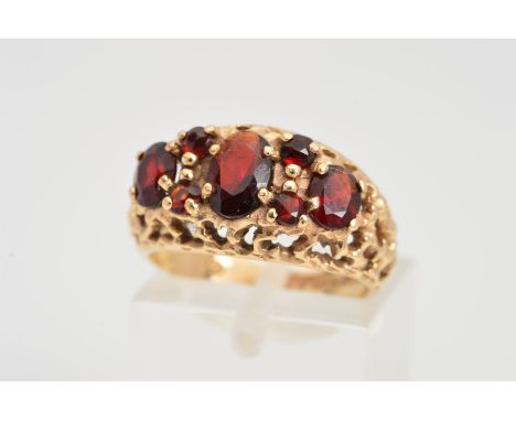 A 9CT GOLD GARNET RING, designed as oval and circular garnets within an open textured surround, 9ct hallmark for Birmingham, 