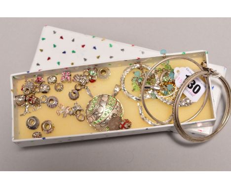 A SELECTION OF SILVER AND WHITE METAL JEWELLERY, to include charms, a triple bangle, pendants, two pairs of hoop earrings and